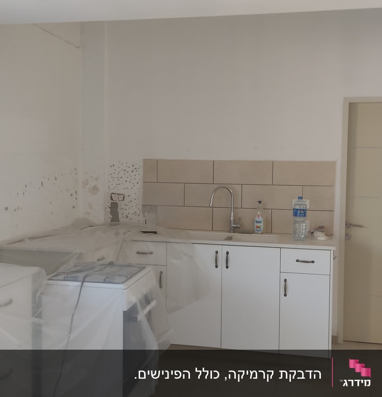 מטבח בשיפוץ עם ארונות מכוסים בניילון